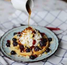 syrup being poured onto a waffle